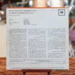 Płyta winylowa w papierowej kopercie. Wytwórca: Columbia [Kolambia]. Miejsce powstania: USA [U eS A], rok tysiąc dziewięćset sześćdziesiąty drugi. Wymiary: trzydzieści na trzydzieści centymetrów. Prawa autorskie: Columbia. [Kolambia] Rewers okładki płyty. Na białym tle napisy, u dołu tytuły nagrań i czasy ich trwania na obu stronach płyty.