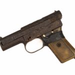 Pistolet Mauser M1914 [eM tysiąc dziewięćset czternaście], kaliber 7,65 [siedem przecinek sześćdziesiąt pięć milimetra] Br [Be er], Niemcy – lata: tysiąc dziewięćset czternaście – tysiąc dziewięćset dwadzieścia trzy. Długość całkowita – około piętnastu centymetrów. Pistolet z prostokątnym chwytem. Chwyt i pałąk spustowy owinięte czarną taśmą. Brak języka spustowego. Lufa i komora nabojowa mocno pordzewiałe. W dolnej części chwytu spust mechanizmu wymiany magazynka. Boczna ściana komory nabojowej karbowana. Część rękojeści w bezpośrednim sąsiedztwie komory nabojowej ukruszona.