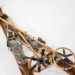 Narty. Twórca: ksiądz Marek Raszewski. Materiał: drewno. Obiekt pochodzi z lat siedemdziesiątych dwudziestego wieku. Para drewnianych nart. Leżą, mają skrzyżowane czubki. Na nartach bambusowe kijki z okrągłymi talerzykami i metalowym kolcem. Uchwyty kijków z pętlami na nadgarstki. Narty z zagiętymi do góry czubkami, wyprofilowanymi tyłami. W ich środkowej części metalowe wiązanie biegowe typu telemark, z pętlą ze stalowej linki.