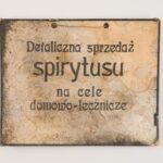 Wywieszka sklepowa. Materiał: tektura i farba drukarska. Technika: nadruk i farba drukarska. Leszno, rok tysiąc dziewięćset trzydziesty. Wymiary: trzydzieści na dwadzieścia cztery centymetry. Prostokatna tabliczka. Na jasnym, zaplamionym i poszarzałym tle napis: „Detaliczna sprzedaż spirytusu na cele domowo -lecznicze”. W górnej części dwaotwory z przewleczonym cienkim sznurkiem.