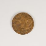 Medal PKOl [Pe Ka Ol], Olimpiada tysiąc dziewięćset osiemdziesiąt. Wykonawca: Mennica Warszawska. Odlew w brązie. Warszawa, tysiąc dziewięćset osiemdziesiąt, średnica siedemdziesiąt milimetrów. Okrągły medal. W jego centralnej części sylwetka nagiego, muskularnego mężczyzny, zwróconego do nas twarzą. Jego sylwetka odpowiada klasycznym proporcjom Witruwiusza. W prawej ręce nad głową trzyma gałązkę oliwną, lewą, zgiętą w łokciu pod kątem prostym zwraca wnętrzem dłoni w naszym kierunku. Po obu stronach sylwetki mężczyzny napis literami stylizowanymi na starożytne – łacińskie. „Igrzyska olimpijskie” Moskwa, tysiąc dziewięćset osiemdziesiąt, Lake Placid [Lejk Plesid] . Napis przedzielony jest sylwetką mężczyzny ułożony w pozornie nieuporządkowany sposób: Napis „Igrzy” znajduje się przy prawym boku, „ska. Olim” przy lewym boku. Poniżej, znów przy prawym boku: „pijskie” i przy lewym: „Moskwa”. Poniżej przy prawym udzie mężczyzny liczba: tysiąc dziewięćset osiemdziesiąt, przy lewym napis: „Lake Placid”.